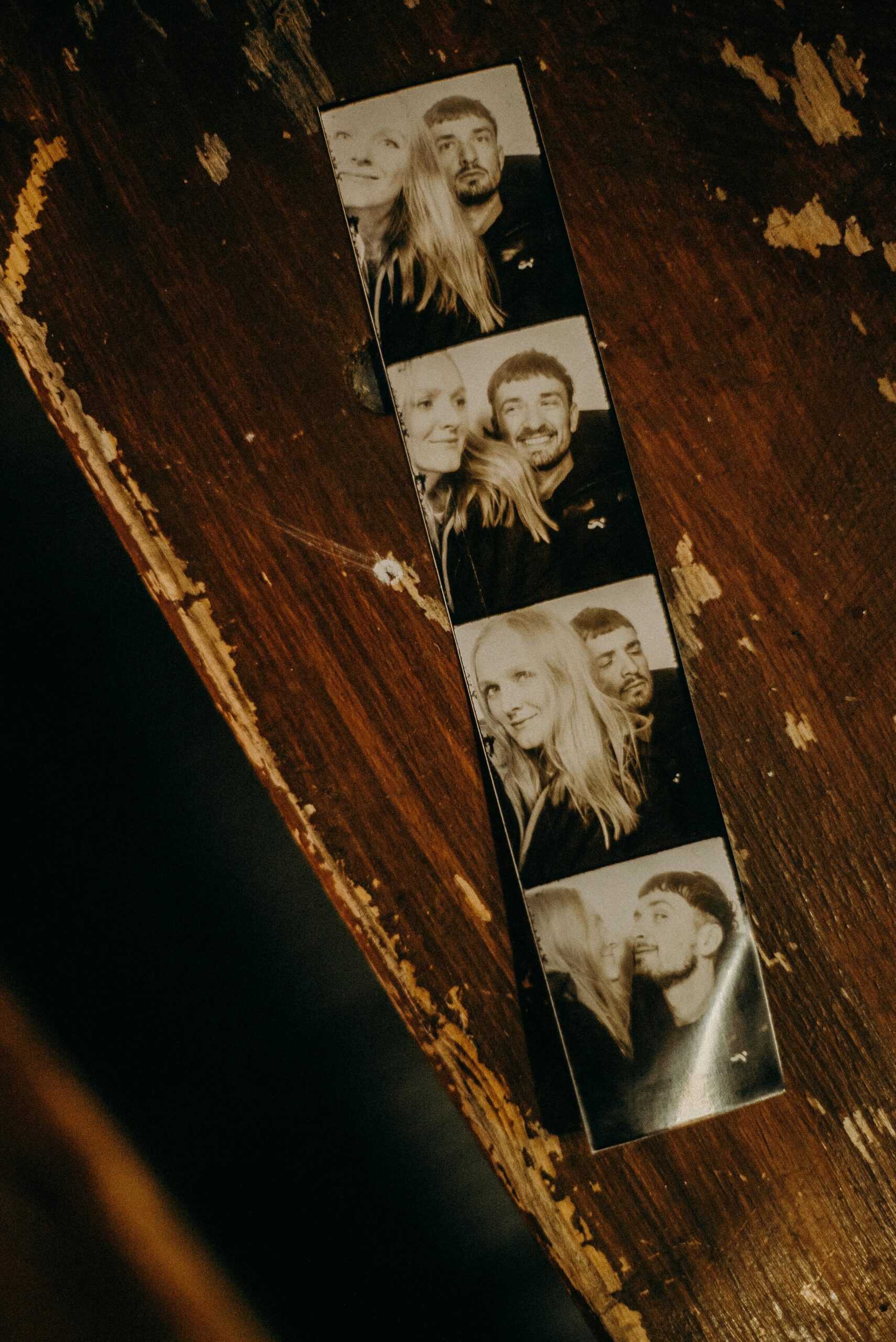A black and white photobooth strip on a rustic wood surface, evoking nostalgia.